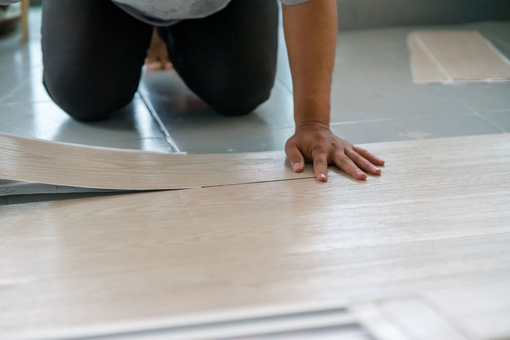 man kneeling down on installing vinyl flooring