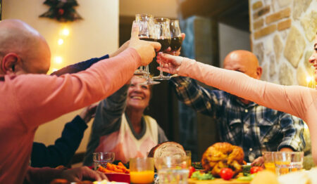 family clinking wine glasses at holiday dinner