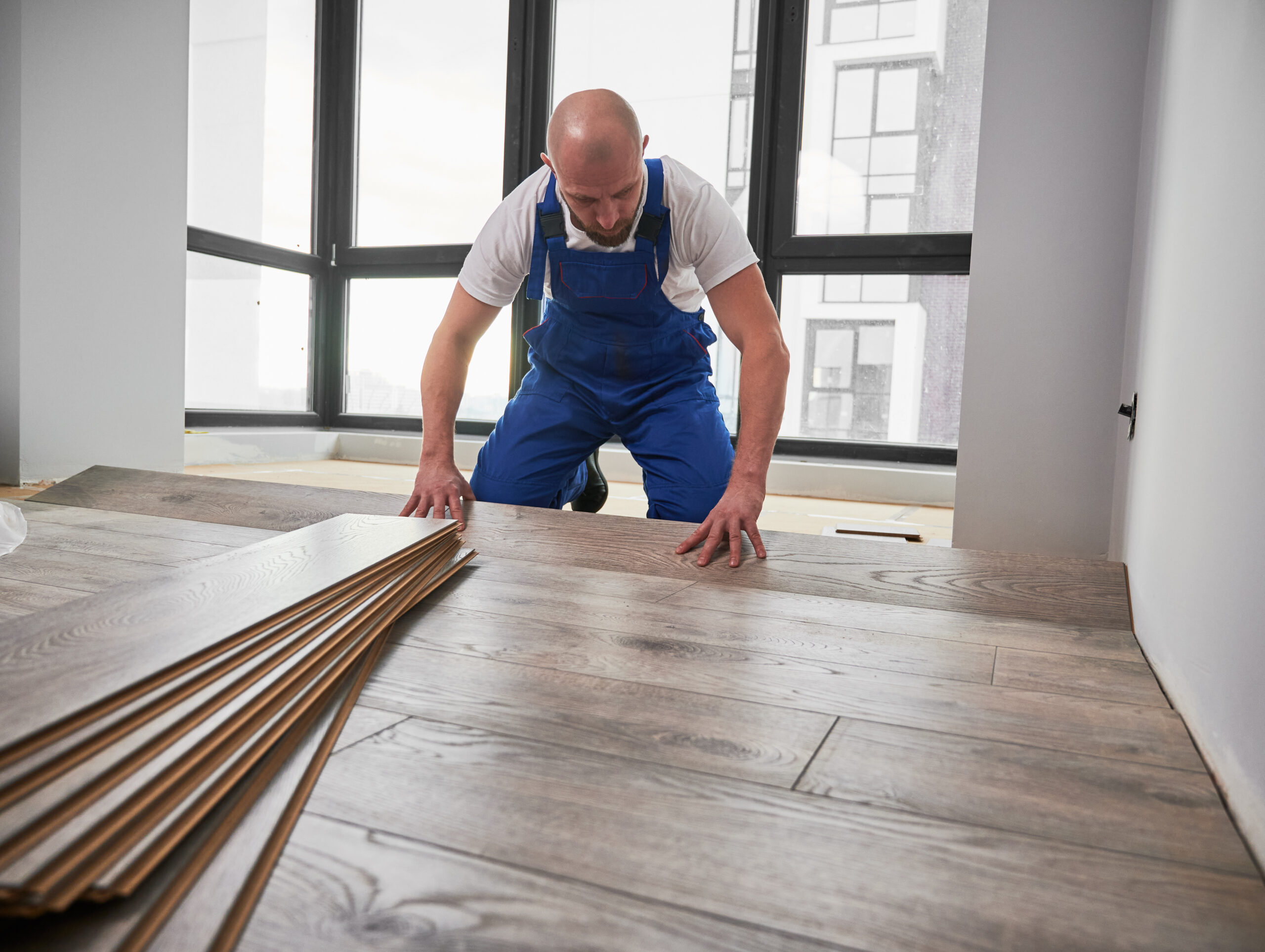 Man installing laminate flooring at home during renovation. man with flooring