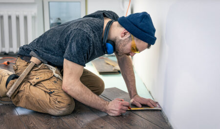 A male worker puts laminate flooring on the floor. Man fixing floor