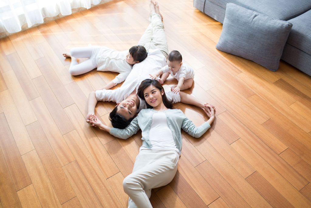 happy-young-family-resting-on-wooden-floor family laying on hardwood floor